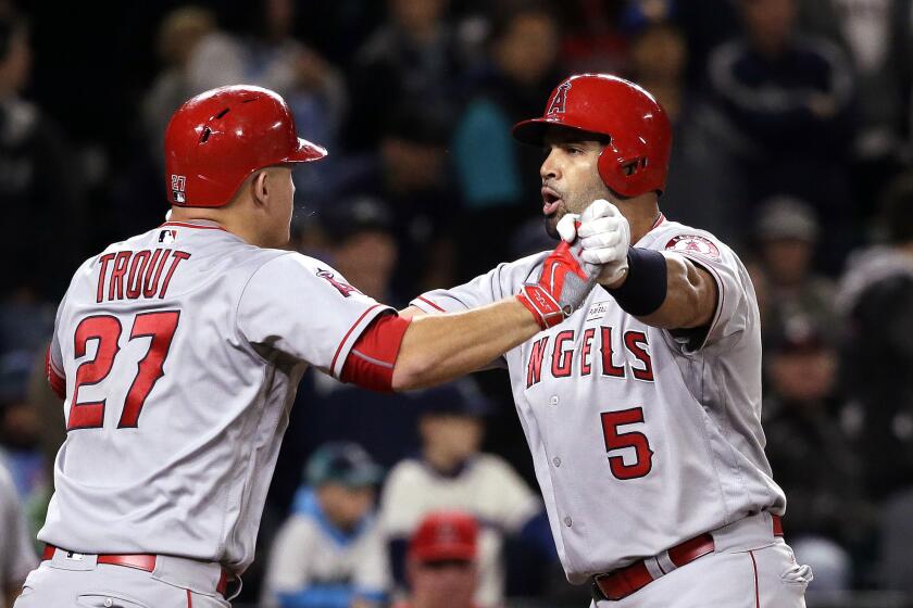 Albert Pujols (5) is greeted at home by Mike Trout (27) after Pujols' three-run home run against the Mariners during the ninth inning of a game on May 14.