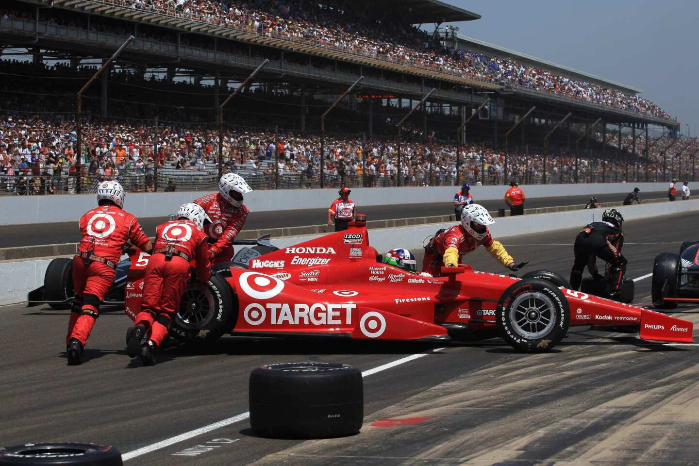 The crew of driver Dario Franchitti tries to get his car into its pit after it was spun by E.J. Viso on Sunday.