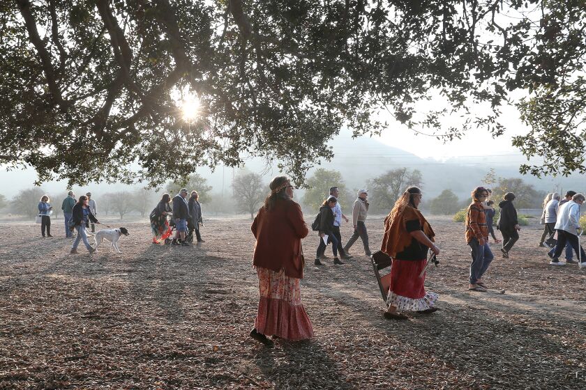 Guests walk under the canopy of the Mother Tree at the new Putuidem Village at the Northern Open Space in San Juan Capistrano after dedication and ribbon cutting ceremony on Friday.