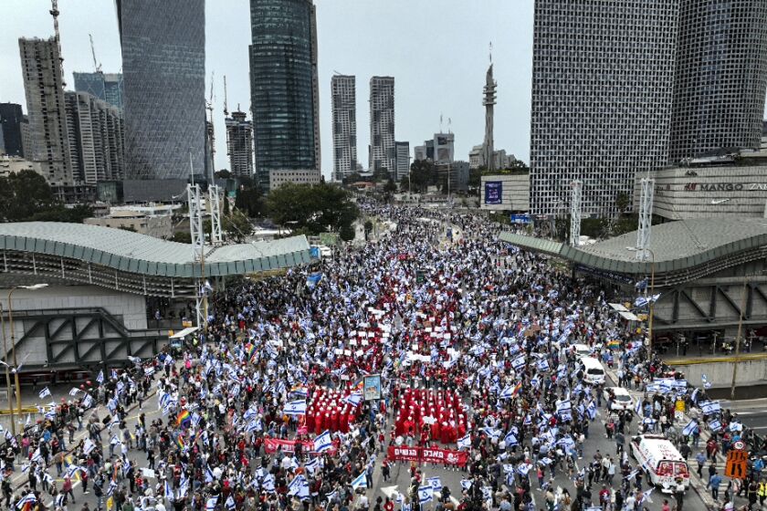 Protesters supporting women's rights dressed as characters from The Handmaid's Tale TV series and other Israelis protest against plans by Prime Minister Benjamin Netanyahu's government to overhaul the judicial system in Tel Aviv, Israel, Thursday, March 23, 2023. (AP Photo/Oded Balilty)