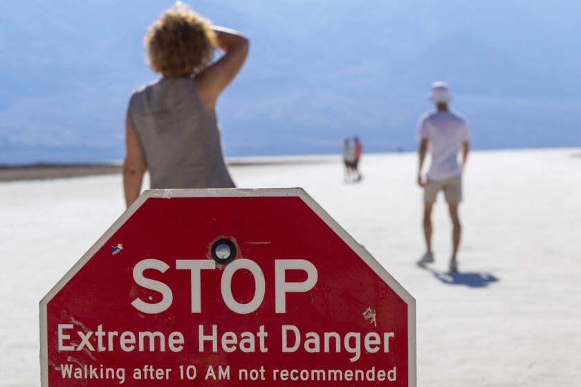 A person wipes sweat from their brow at Badwater Basin in Death Valley National Park, Calif., Sunday, July 7, 2024. Forecasters say a heat wave could break previous records across the U.S., including in Death Valley. (AP Photo/Ty ONeil)