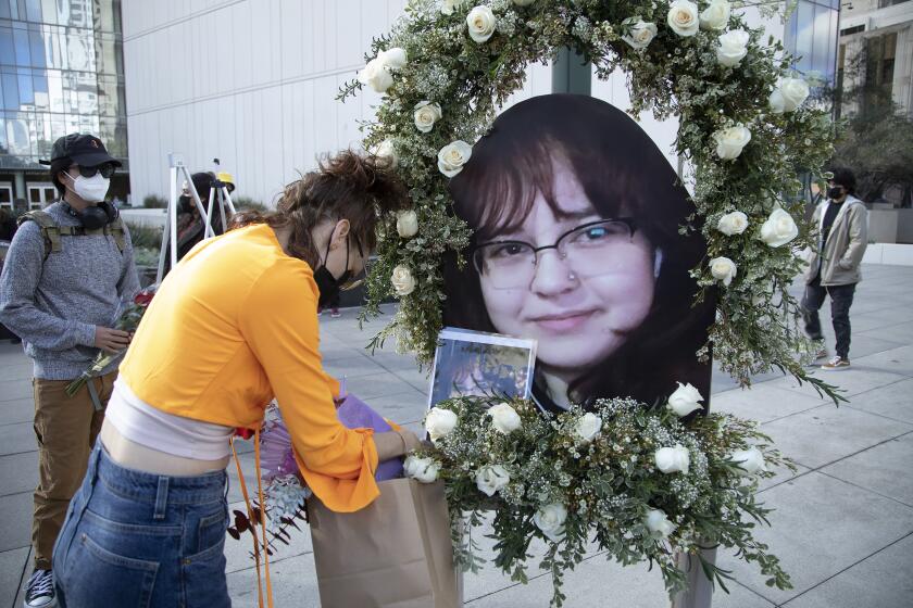 A woman places flowers near a photo of a shooting victim.