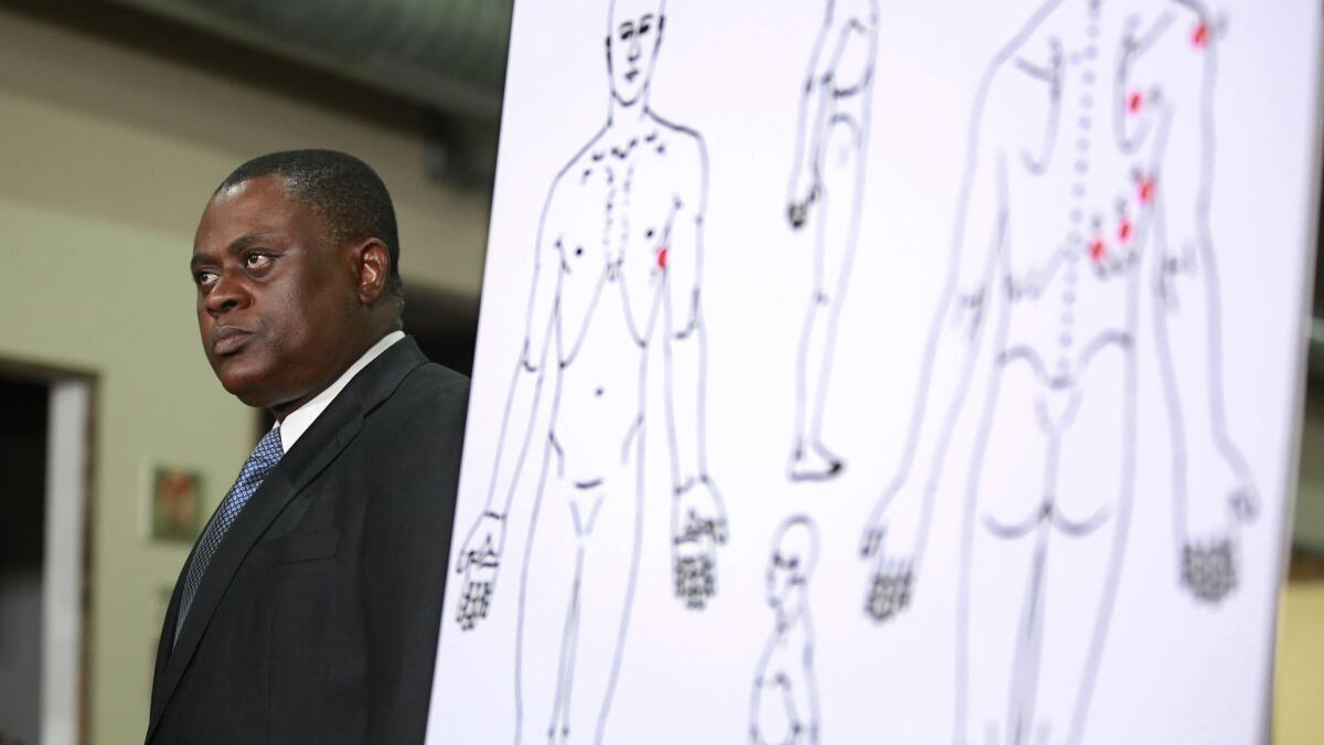 Dr. Bennet Omalu stands next to a diagram showing where Stephon Clark was struck by bullets.