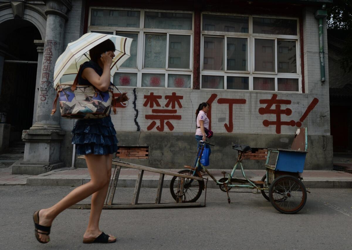 A Chinese woman walks past an old house in Beijing.