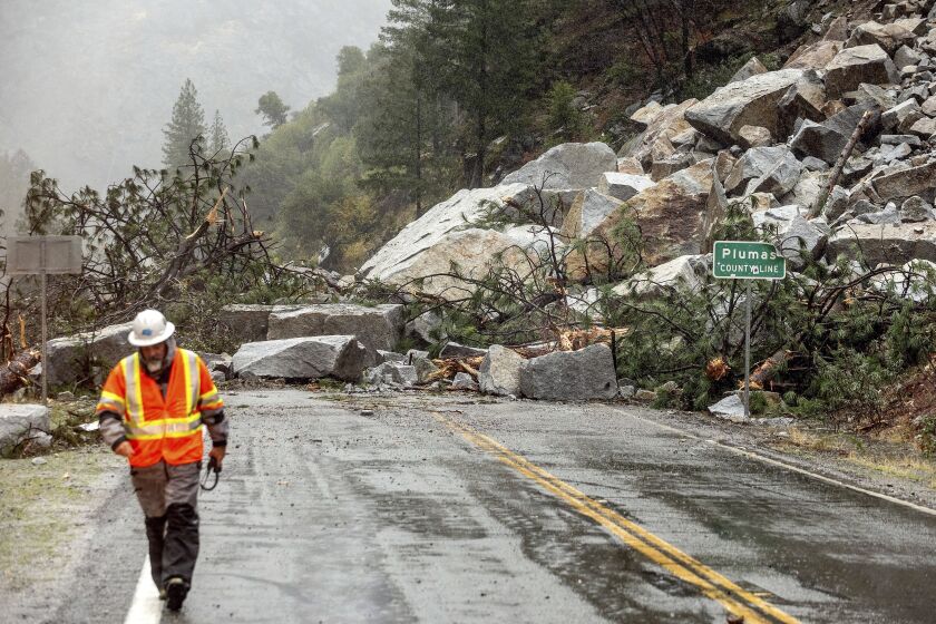 Caltrans maintenance supervisor Matt Martin walks by a landslide covering Highway 70 in the Dixie Fire zone on Sunday, Oct. 24, 2021, in Plumas County, Calif. Heavy rains blanketing Northern California created slide and flood hazards in land scorched during last summer's wildfires. (AP Photo/Noah Berger)