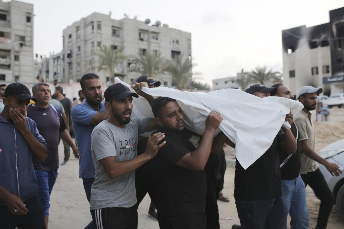 Palestinians carry a person killed by Israeli bombardment 
