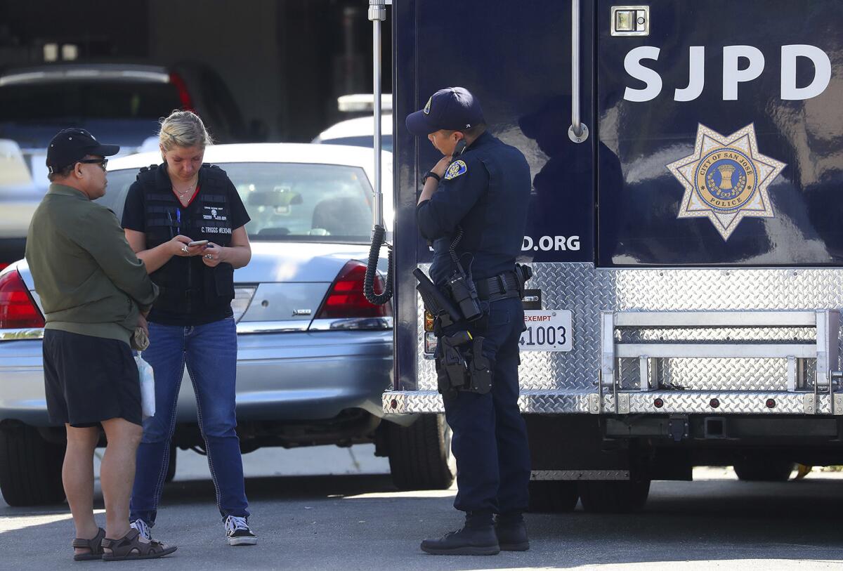 San Jose police talk with an unidentified man near the site of a quadruple murder and suicide.