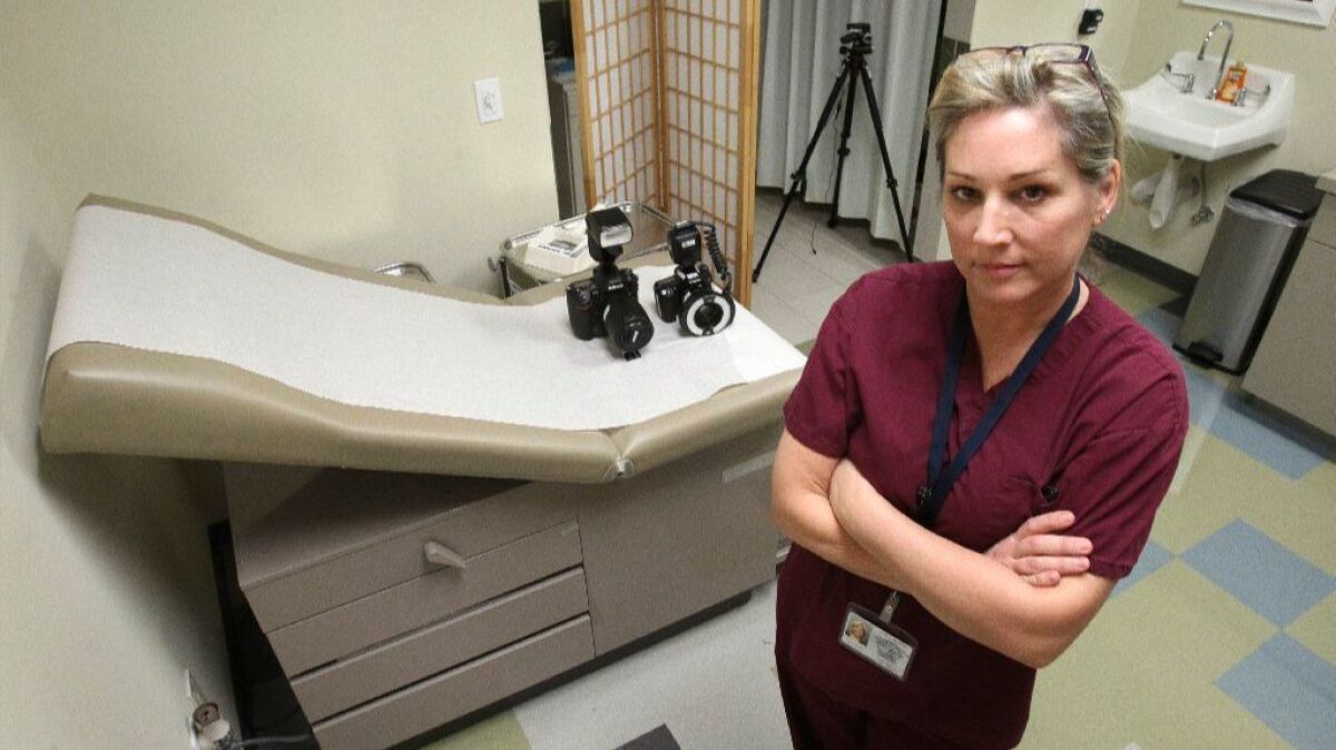 In this March 2017 photo, Karen Marcus, a forensic nurse with Palomar Medical Center, is shown at downtown San Diego's Family Justice Center in the medical unit where victims of domestic violence are examined. She is shown with the cameras she uses on the bed next to her.