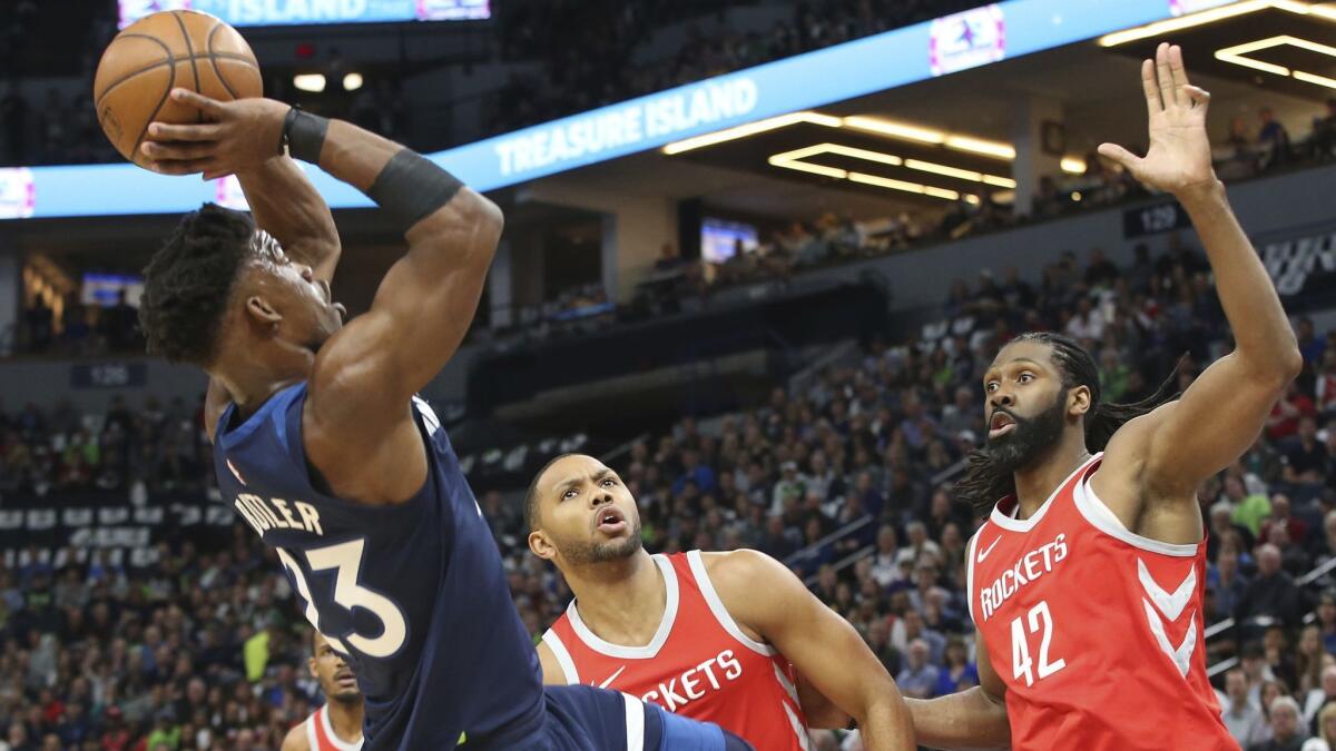 Minnesota Timberwolves' Jimmy Butler shoots as Houston Rockets' Eric Gordon, center, and Nene attempt to contest the shot.