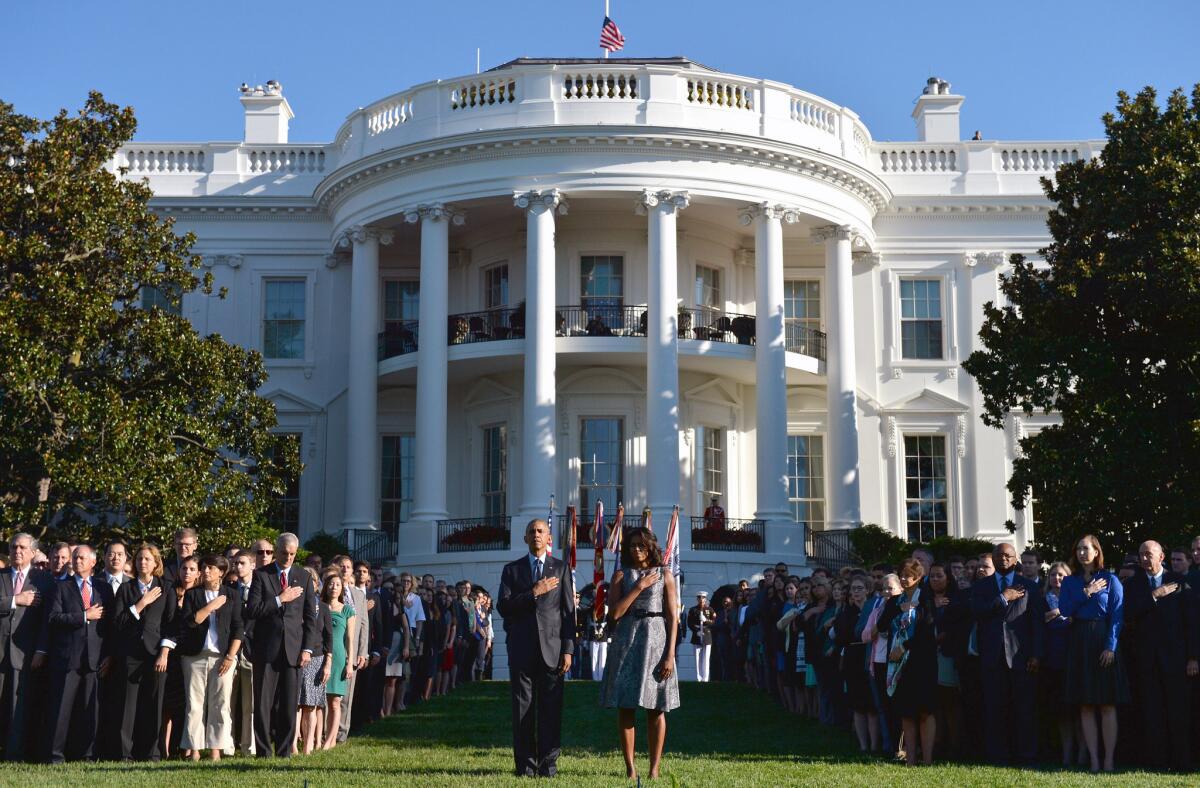 President Obama and First Lady Michelle Obama, joined by White House staff, stand as "Taps" is played at the White House on the 14th anniversary of the Sept. 11 terrorist attacks on the United States.