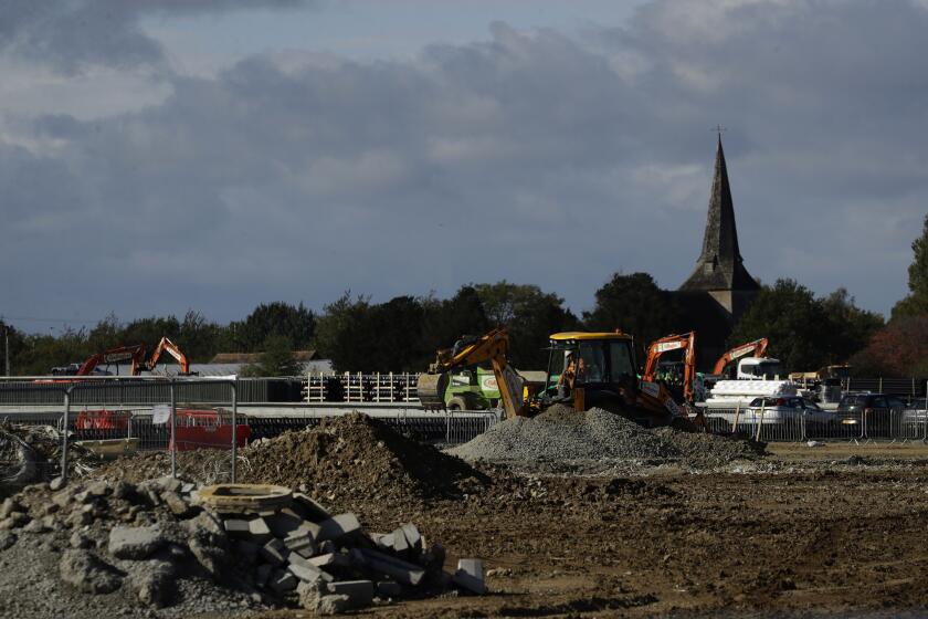 Construction takes place backdropped by the spire of St Mary's Church, of which parts date back to the 12th century, on a post-Brexit customs clearance border post facility on land that was previously a field between the villages of Mersham and Sevington in the county of Kent, south east England, Tuesday, Oct. 6, 2020. In the corner of Britain known as the Garden of England, Brexit is literally taking concrete form. Diggers, dump trucks and cement mixers are transforming a field in the village of Sevington into a customs clearance depot with room for up to 2,000 trucks. It's part of Britain's new border with the European Union, and no one asked the locals for their permission. (AP Photo/Matt Dunham)