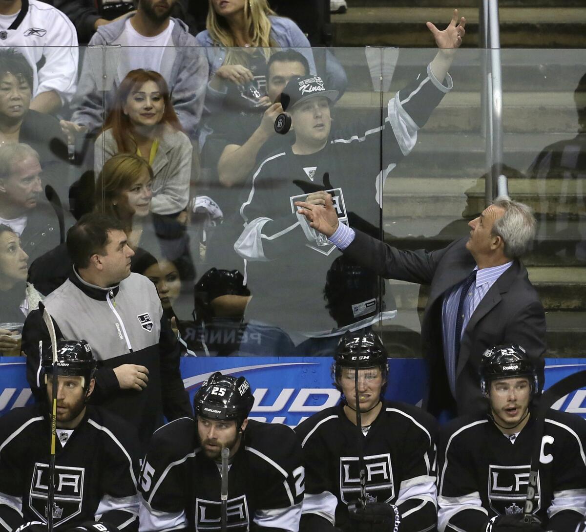 Kings coach Darryl Sutter tosses a puck to fans after it was shot into the bench area during Game 5 of the NHL Western Conference semifinal against San Jose at Staples Center.