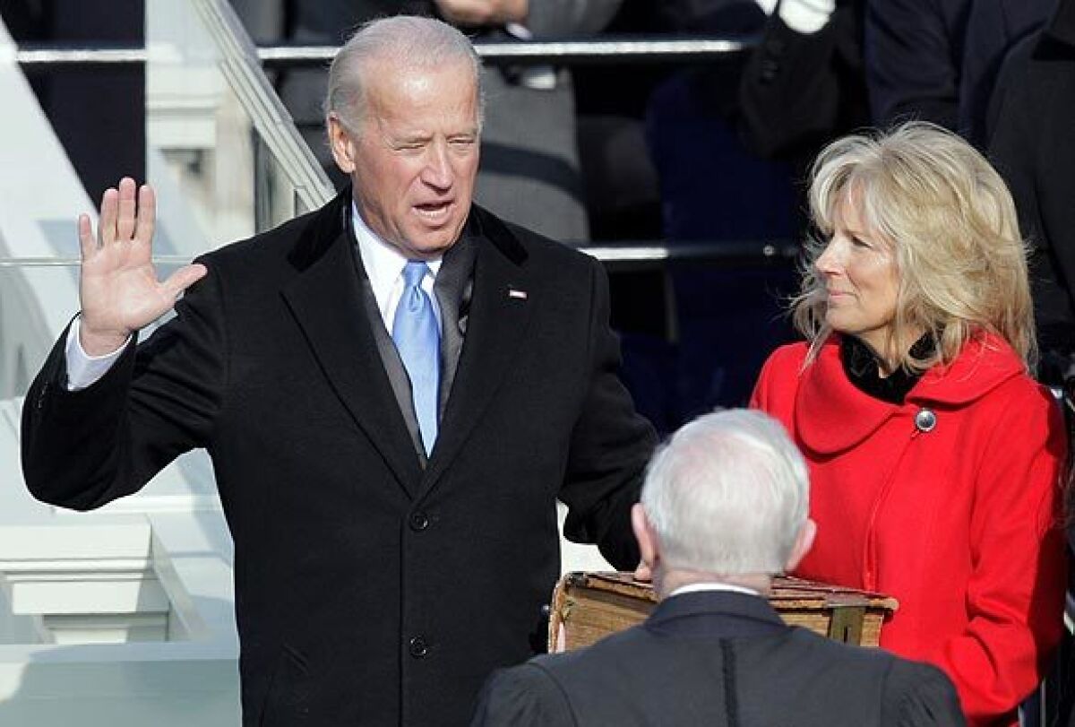 Vice President Joe Biden holds up his hand and takes the oath of office while Jill Biden holds a Bible