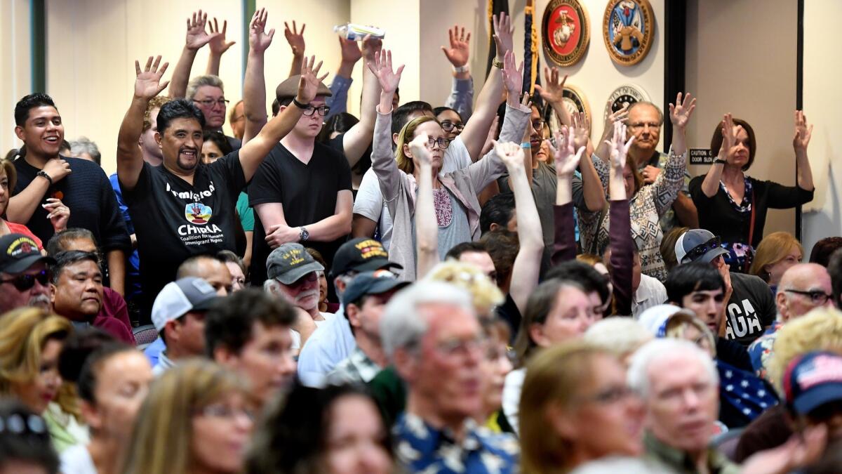 Supporters of the "sanctuary state" law raise their hands at Santa Clarita City Hall before a vote Tuesday.