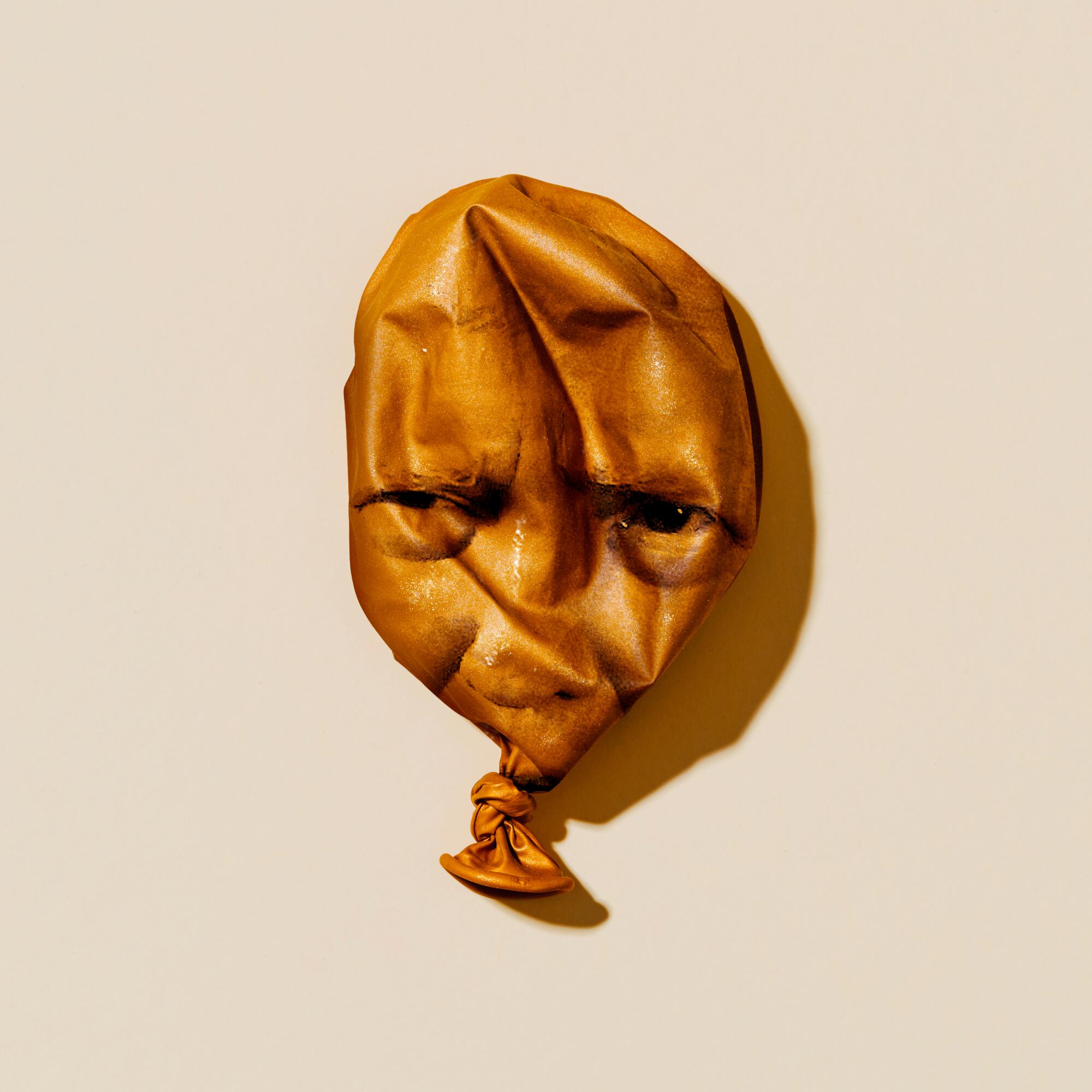 Photo illustration of a deflated gold balloon with Donald Trump's face on it.