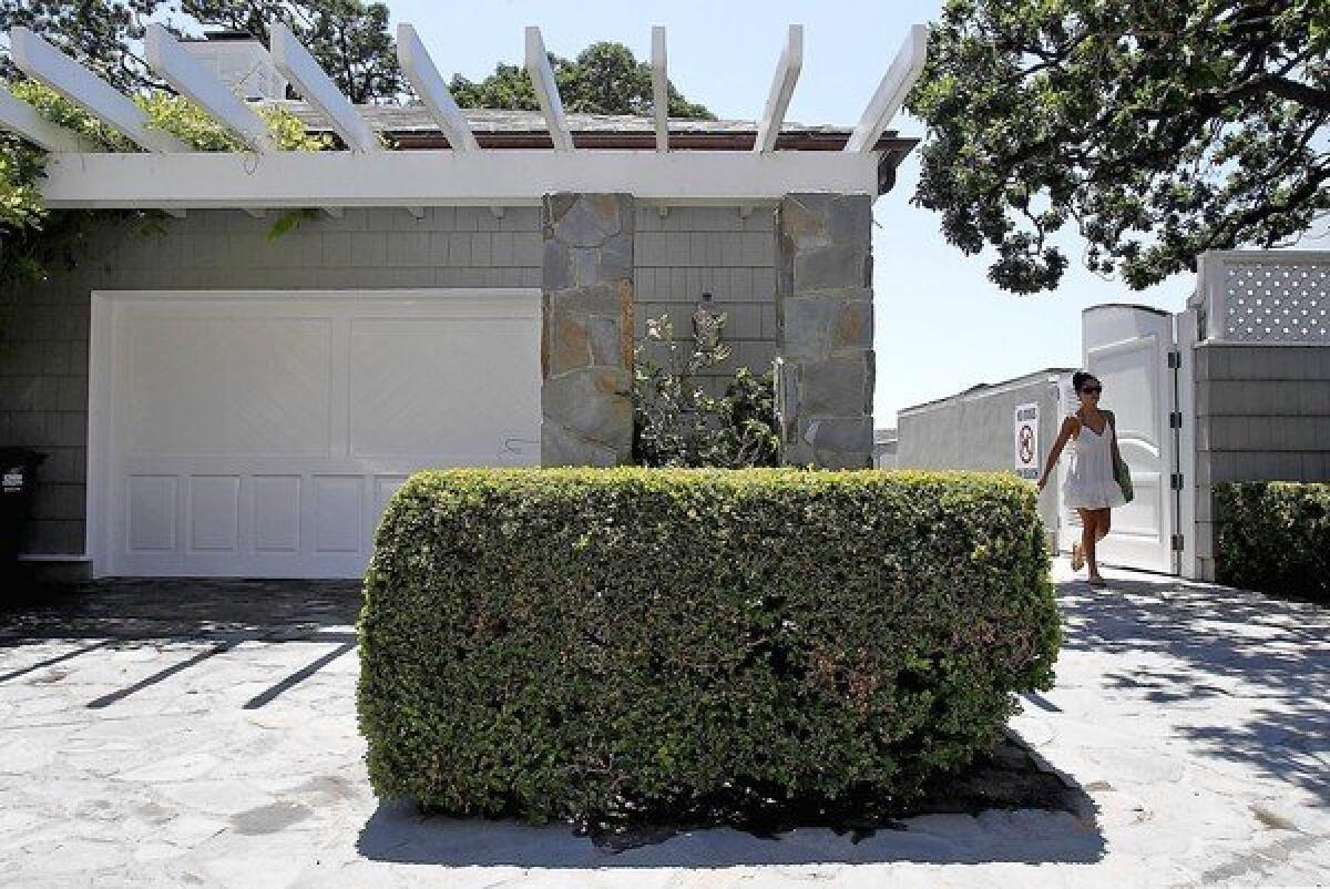 A beachgoer passes through white wooden gates that look like an elegant extension of music and film mogul David Geffen's home at Carbon Beach in Malibu. The opening of the gates in 2005 marked a rare victory for beach visitors.