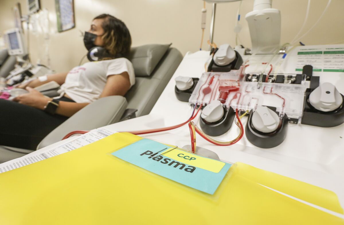 A woman sits as a machine removes her blood for a plasma donation