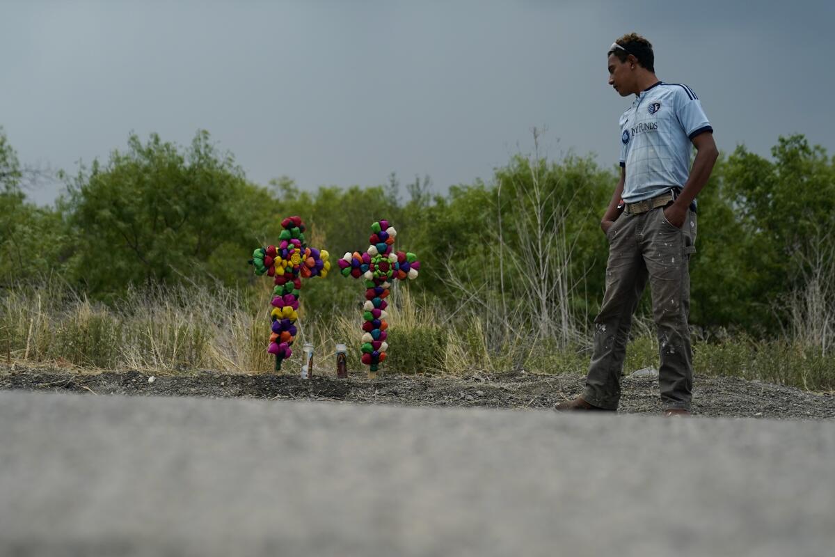 A man stands beside two roadside crosses