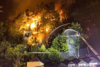 Firefighters throw water on fire in the Ceske Svycarsko (Czech Switzerland) National Park, above the village Hrensko, Czech Republic, Monday July 25, 2022. The fire broke out on Sunday and started spreading on Monday as the wind rose. (Hajek Vojtech/CTK via AP)