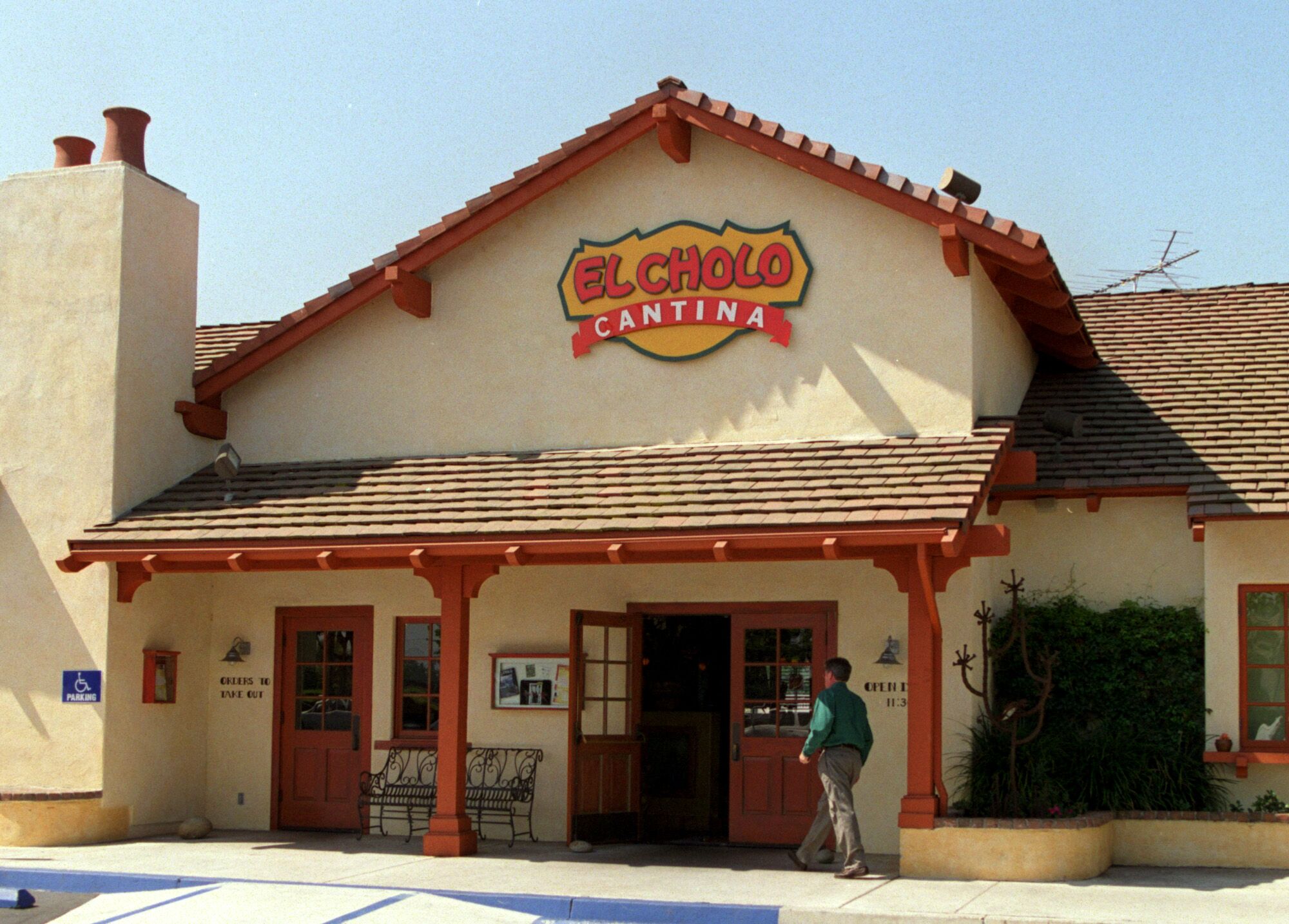 A person walks up to El Cholo Cantina in Irvine, housed in a Spanish-style building.