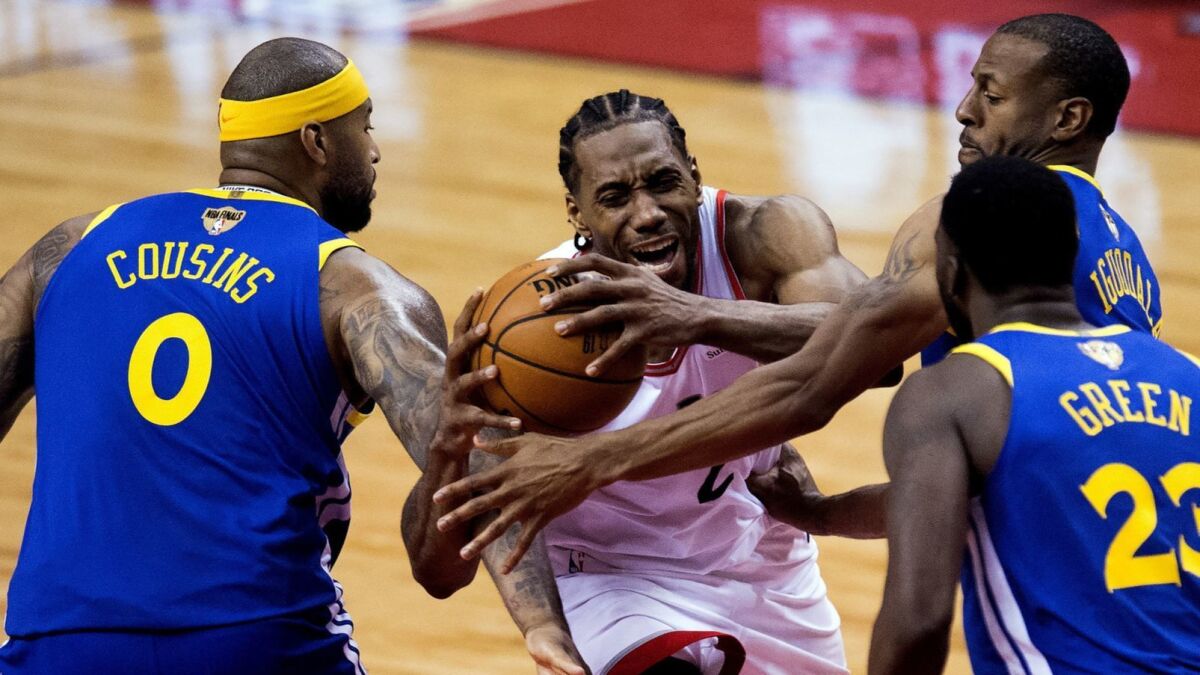 Raptors forward Kawhi Leonard draws a foul as he drives down the lane against center DeMarcus Cousins, forward Draymond Green and forward Andre Iguodala during the second half of Game 5.