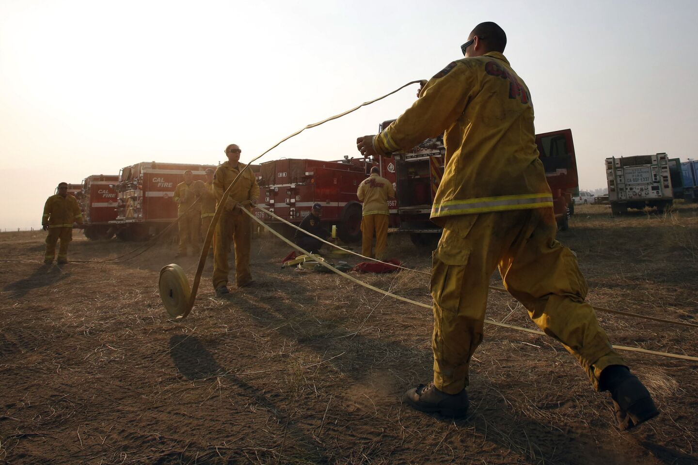 Firefighters prepare hoses at Mountain Fire Base Camp set up along Highway 74 in Mountain Center.