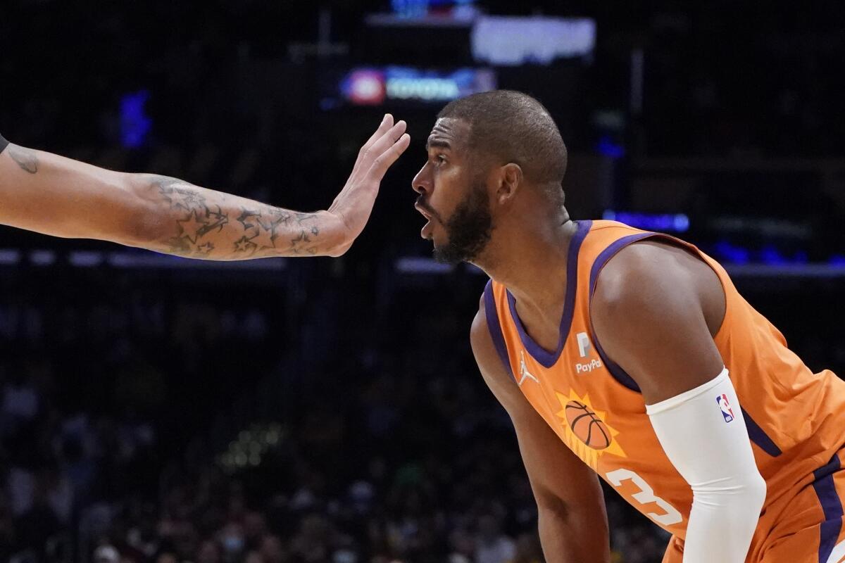 Anthony Davis (izquierda), de los Lakers de Los Ángeles, pone la mano frente de la cara de su rival de los Suns.