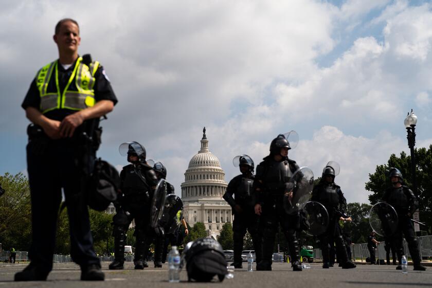 WASHINGTON, DC - SEPTEMBER 18: U.S. Capitol Police officers in gear, stand with the dome of the Capitol in the background as people gather at Union Square near the Capitol Reflecting Pool, facing the West Front of the U.S. Capitol Building for the "Justice for J6 Rally" on Saturday, Sept. 18, 2021 in Washington, DC. (Kent Nishimura / Los Angeles Times)