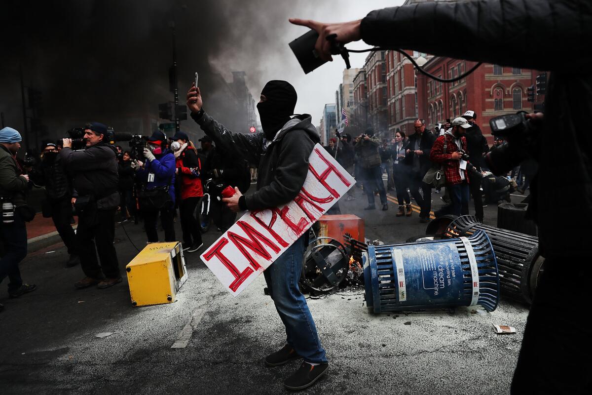 A protester takes a picture while holding a sign that reads "Impeach" in downtown Washington, D.C., following the inauguration of President Trump.