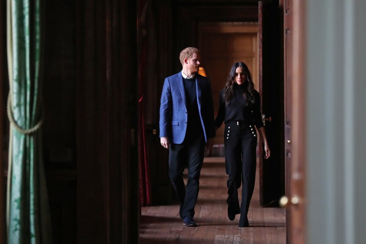 Prince Harry and Meghan Markle walk through the corridors of the Palace of Holyroodhouse on their way to a reception in Edinburgh, Scotland.