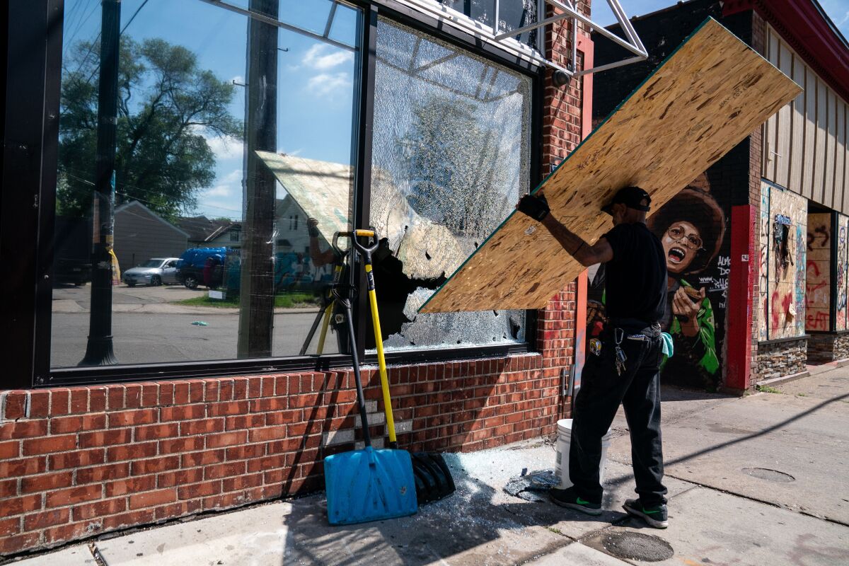 A man boards up the window of a business hit by gunfire 
