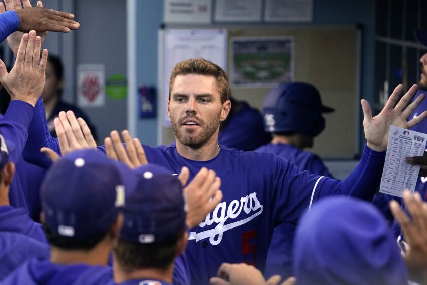 Los Angeles Dodgers' Freddie Freeman is congratulated by teammates in the dugout.