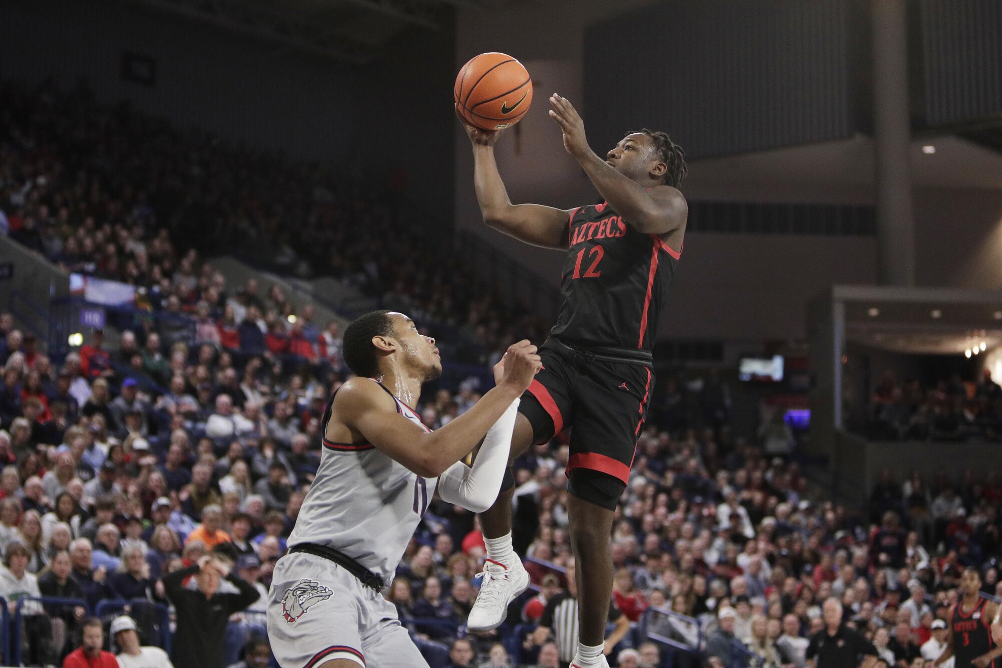 Guard Negara Bagian San Diego Darrion Trammell (12) melepaskan tembakan saat mendapat tekanan dari guard Gonzaga Nolan Hickman.
