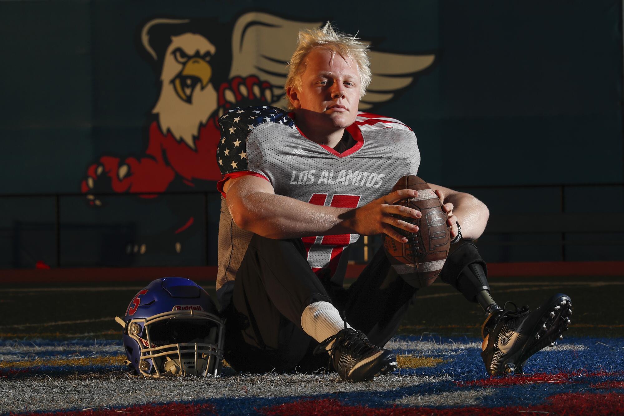 Los Alamitos long snapper Carson Fox looks at the camera while sitting on a football field.