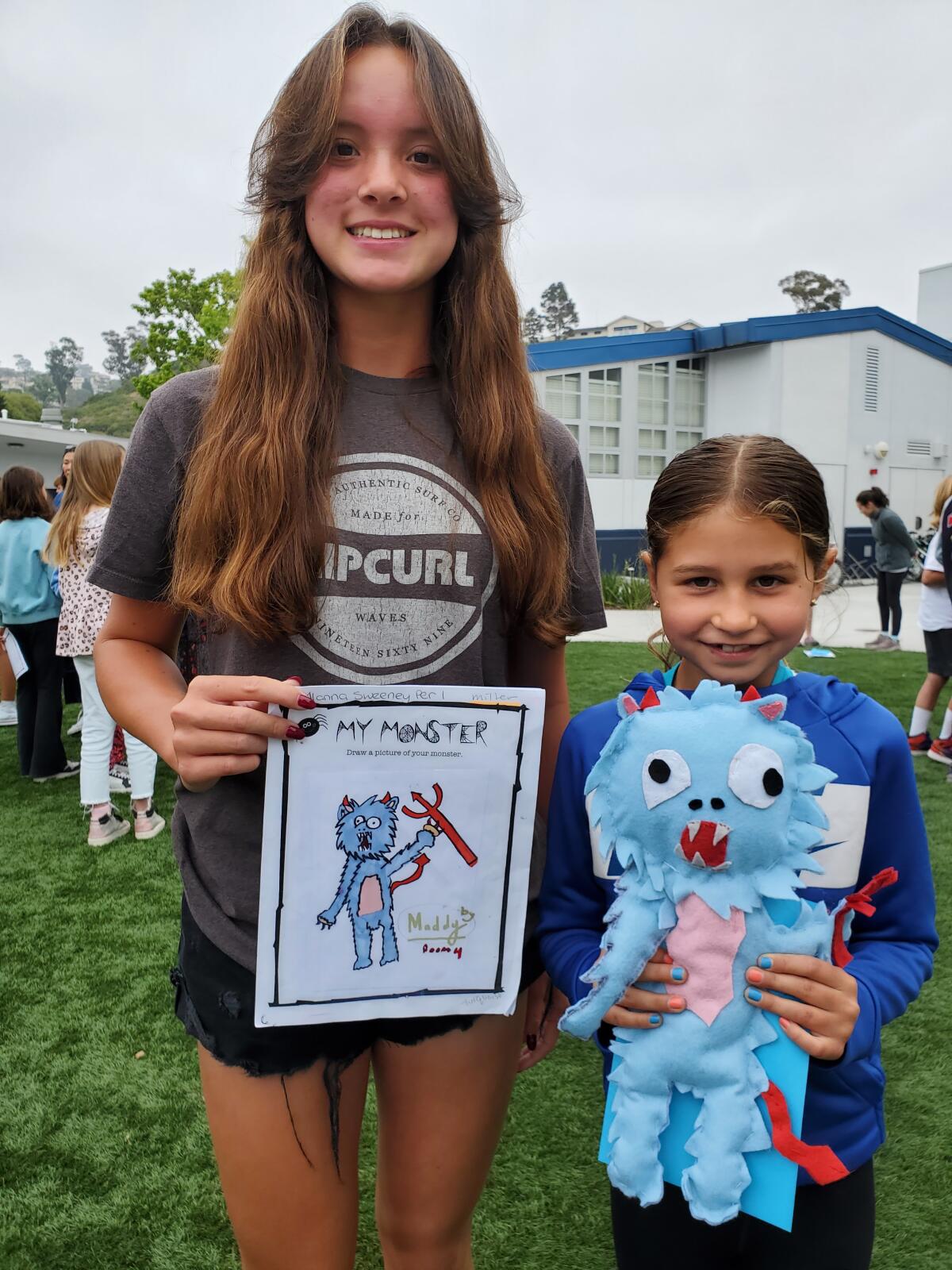 Seventh-grader Alanna Sweeney stands with third-grader Maddy Wade with the monster Alanna made based on Maddy's drawing.