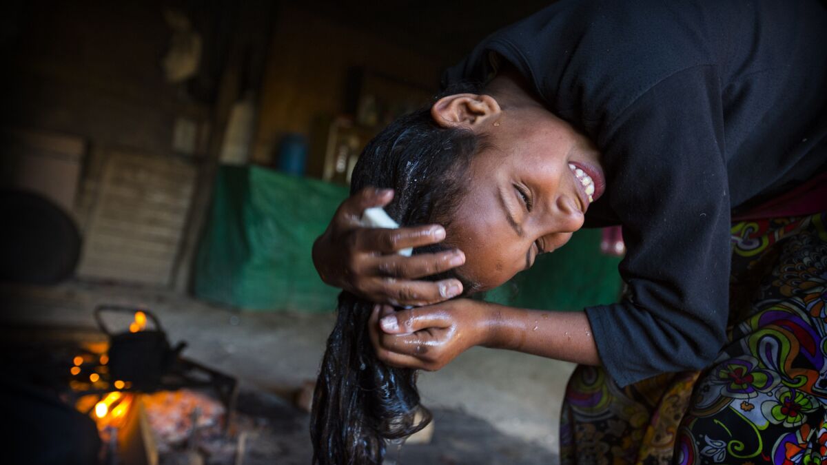 12-year old Nasrin washes hair using a bucket before heading out to school.