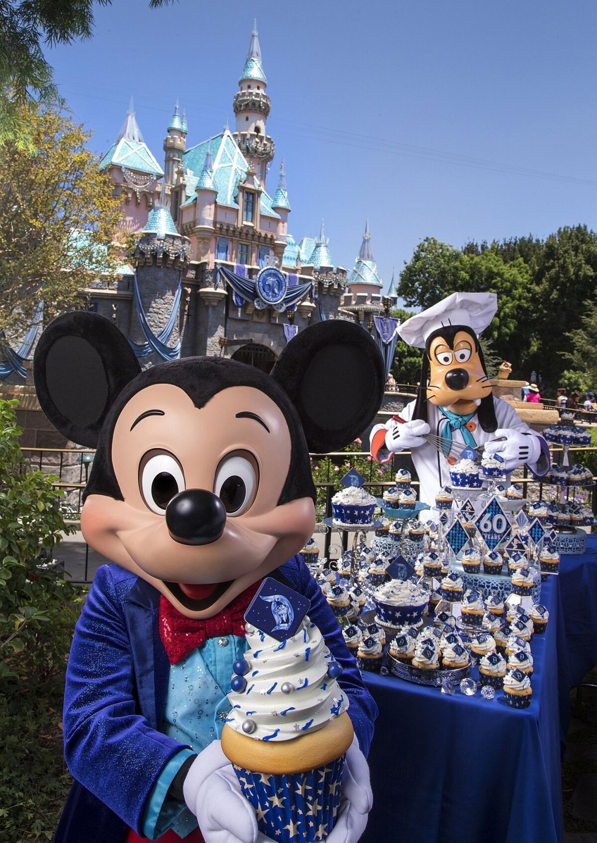 ANAHEIM, CA - JULY 16: In this handout photo provided by Disney Parks, on the eve of the 60th anniversary of the Disneyland Resort, Mickey Mouse and Goofy help prepare celebratory cupcakes July 16, 2015 at Disneyland park in Anaheim, California. Disneyland Resort park guests will receive a complimentary cupcake on Thursday, while supplies last, as the original Disney theme park marks 60 years since its July 17, 1955 grand opening. Celebrating six decades of magic, the Disneyland Resort Diamond Celebration features three new nighttime spectaculars that immerse guests in the worlds of Disney stories like never before with "Paint the Night," the first all-LED parade at the resort; "Disneyland Forever," a reinvention of classic fireworks that adds projections to pyrotechnics to transform the park experience; and a moving new version of "World of Color" that celebrates Walt Disney's dream for Disneyland. (Photo by Paul Hiffmeyer/Disneyland Resort via Getty Images) ** OUTS - ELSENT, FPG - OUTS * NM, PH, VA if sourced by CT, LA or MoD **