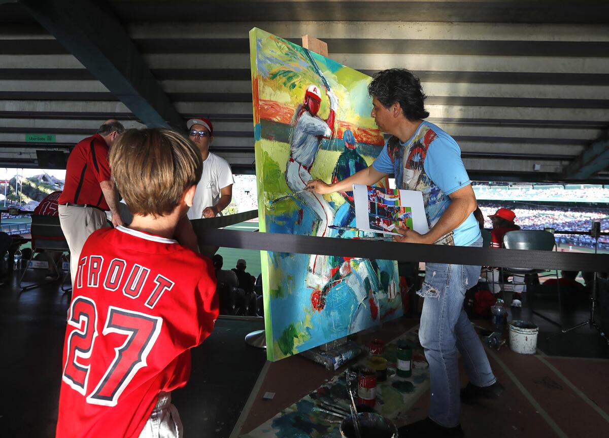 Local artist Hugo Rivera paints a canvas of Angels superstar Shohei Ohtani Wednesday at Angels Stadium.