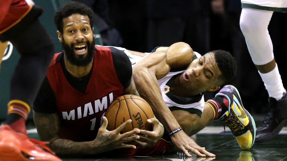 Heat forward James Johnson and Bucks forward Giannis Antetokounmpo battle for a loose ball during their game Wednesday night.