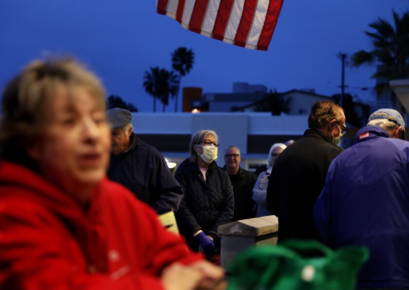 Eileen Oda Leaf, 67, center, wears a mask while waiting with other seniors outside Gelson's Market in Manhattan Beach during a seniors shopping hour early on Wednesday, March 18, 2020.