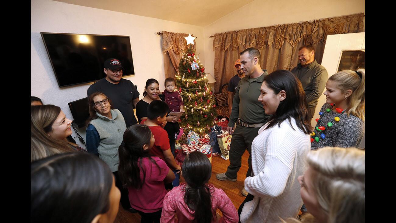 After gathering at headquarters for the annual Glendale Police Department Cops for Kids Toy Distribution event, volunteers including officer Mike Wolner, center, delivered Christmas gifts to 28 local families, including the Aparicio and De La Cruz families who live in one home, in Glendale on Thursday, Dec. 14, 2017.