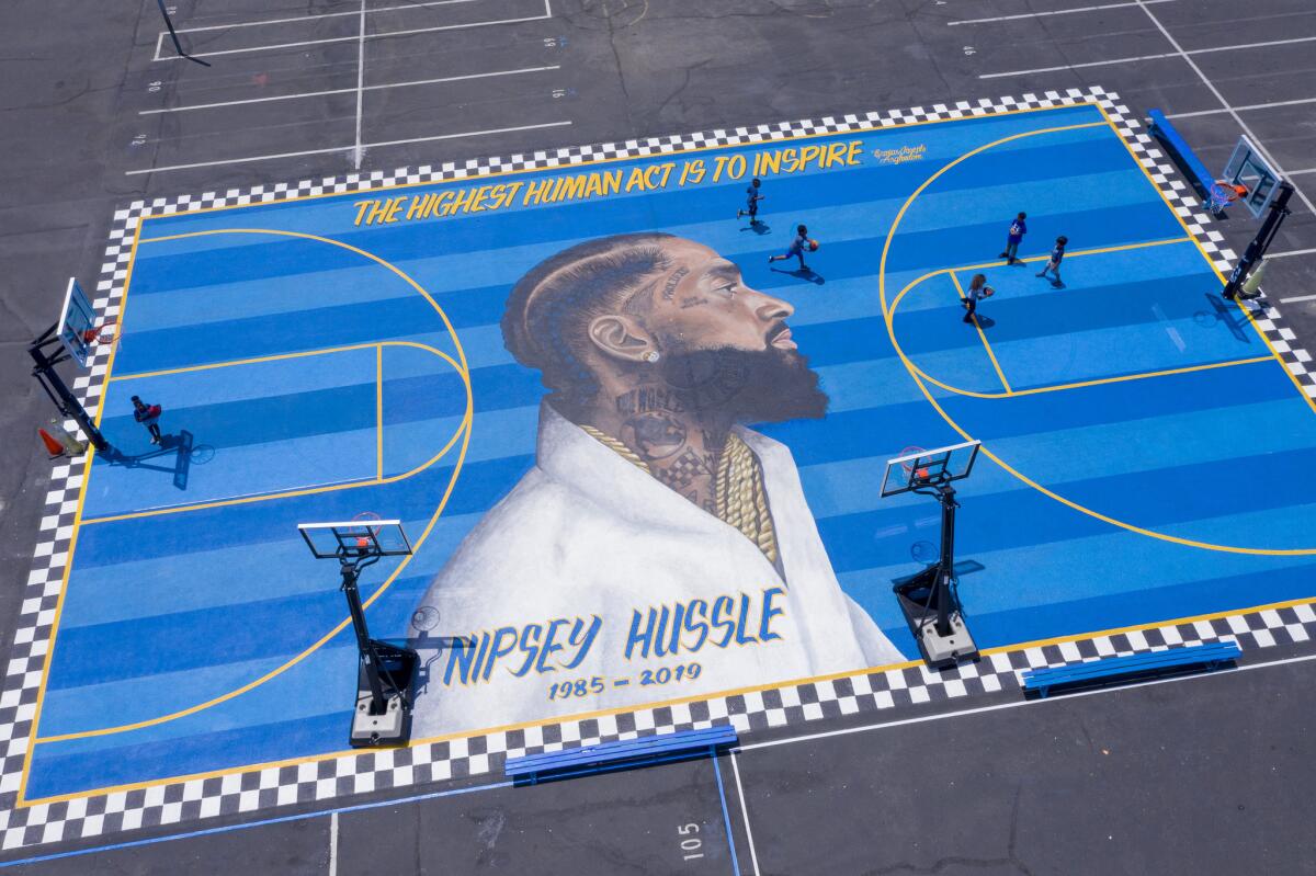 Children at the Crete Academy play basketball on a court painted with a mural of Nipsey Hussle.