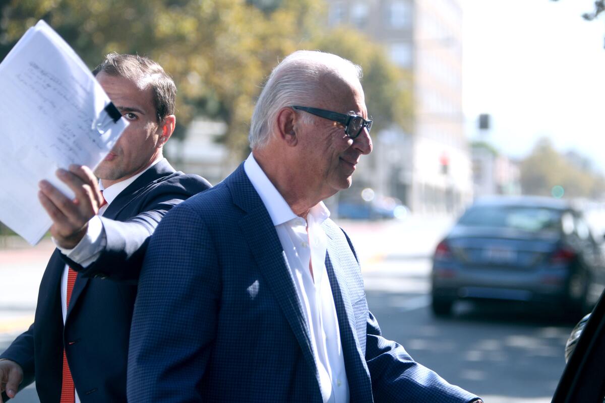 Honolulu Manor Senior Apartments owner Elias Shokrian, right, heads to his car as his attorney Thomas Sands, left, tries to block the camera, outside the Glendale Courthouse after a Sept. 25 hearing about problems with the elevators at the Montrose building. A reader thinks Shokrian should be arrested for elder abuse.