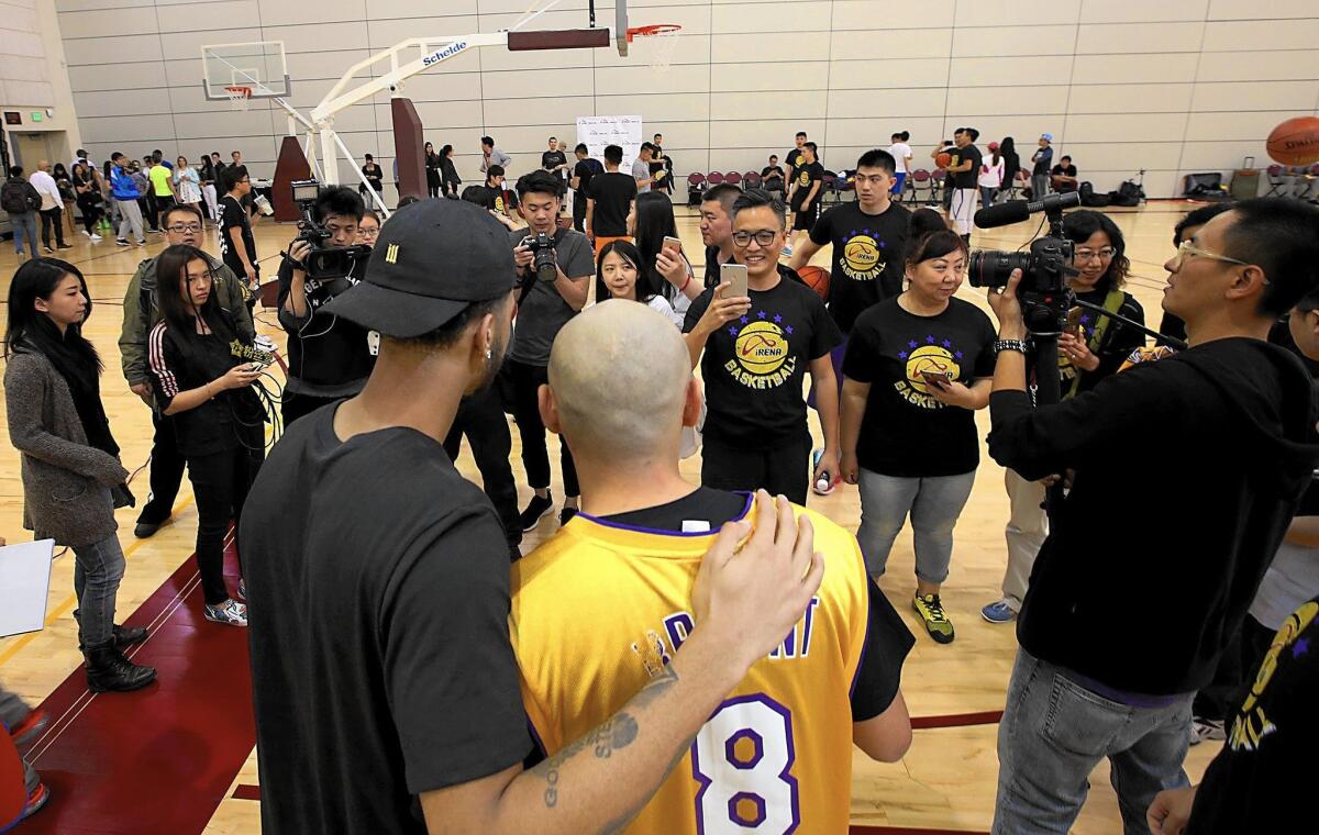 Members of a Chinese tour group in L.A. to watch Kobe Bryant's last NBA game pose for pictures with Lakers guard D'Angelo Russell at an event Tuesday at USC.