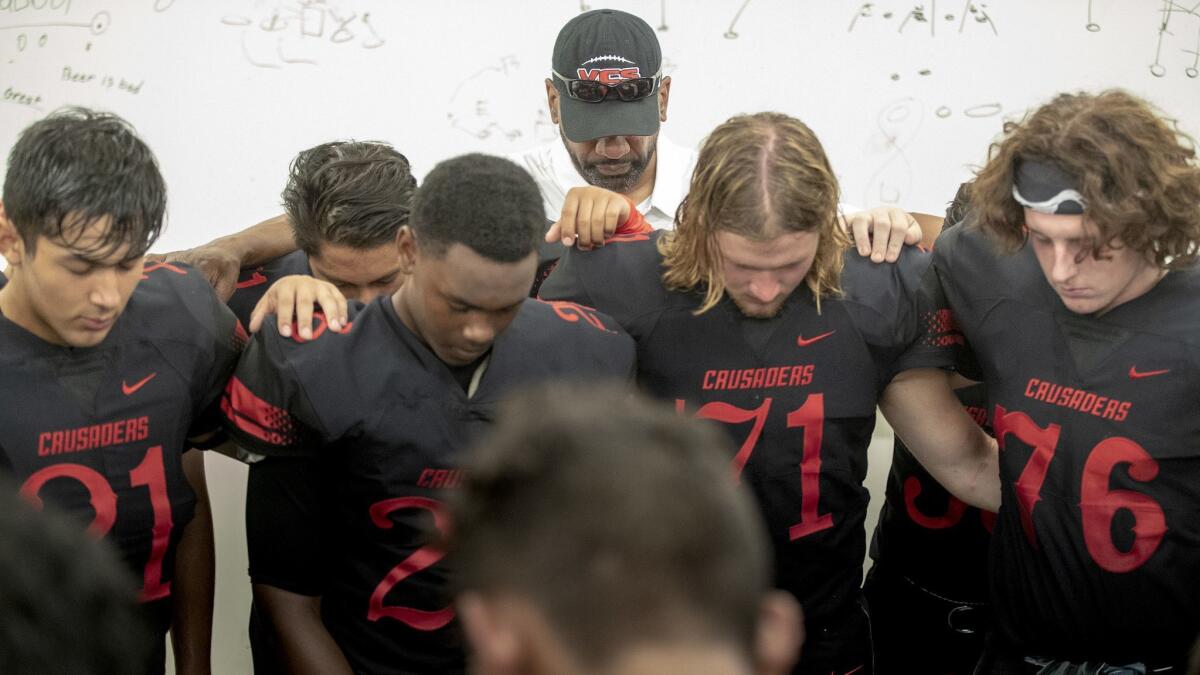 Former USC running backs coach Todd McNair prays with players before the game with his Village Christian Crusaders in Burbank on Friday.