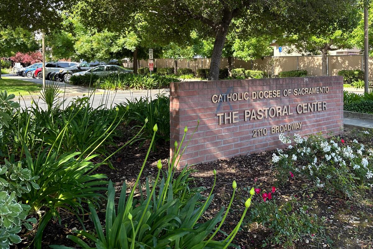 A red-brick wall with gold-letter sign that reads" Roman Catholic Diocese of Sacramento. The Pastoral Center." 