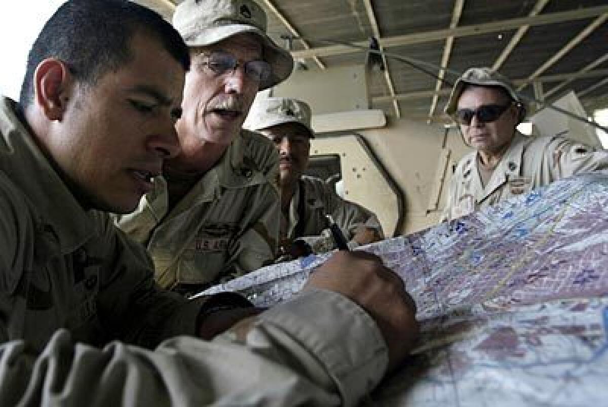 Staff Sgt. Carlys Peters, second from left, and 1st Sgt. Paul Balboa, right, go over a map with other troops. The two men, both older than 50, have seen warfare in Vietnam as well as Iraq. Though they are ribbed about their age, they have much to teach.