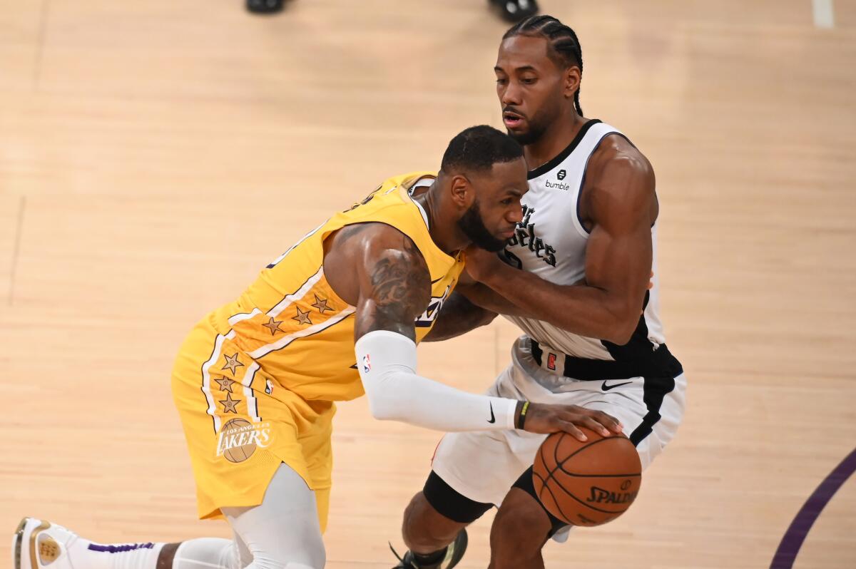 The Lakers' LeBron James drives on the Clippers' Kawhi Leonard on Dec. 25, 2019, at Staples Center.