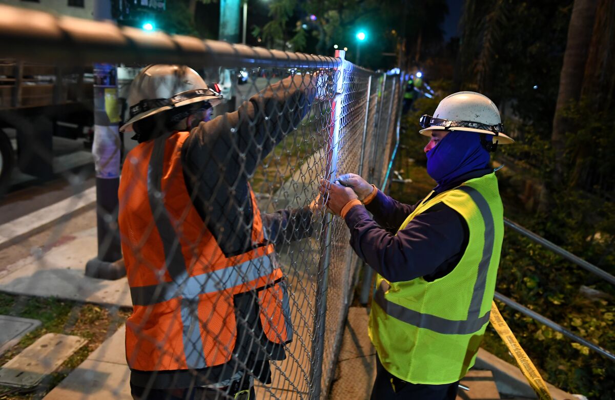 Work crewes install a fence around Echo Park Wednesday night.
