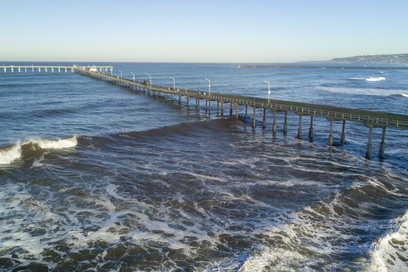Waves rolled under the Ocean Beach pier and lapped on the sea wall in Ocean Beach, San Diego, on the first King Tide of the decade on Friday, January 10, 2020.